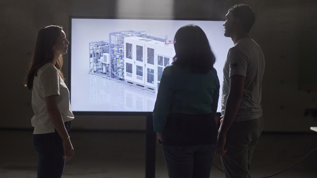 Three engineers looking at 3D rendering of PEM electrolyzer
