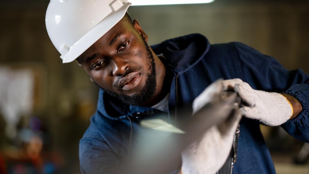 African American welder checking metal frame parts for welding accuracy