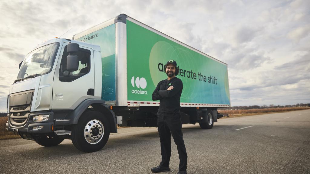Truck diver with arms crossed standing in front of an electric truck powered by Accelera technology
