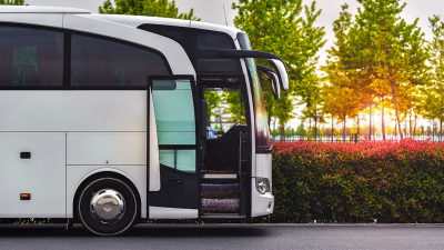 White bus parked on the side of the road next to trees and flowers