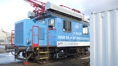 Blue freight locomotive with red railings hooked up to an electric charger