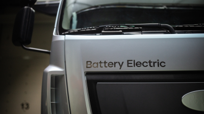 Front of a silver truck cab with the worlds "battery electric" above the grill plate.