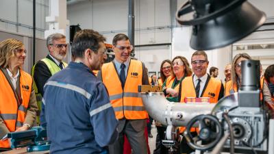 Spain Prime Minister and others in orange safety vests looking at electrolyzer equipment