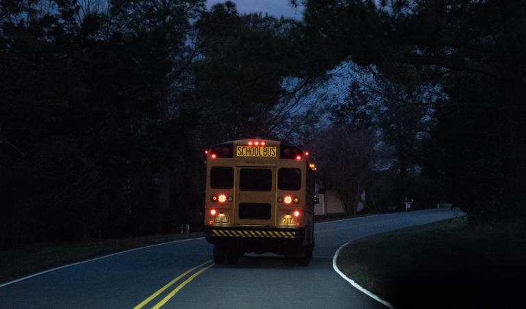 School bus driving through neighborhood before daylight