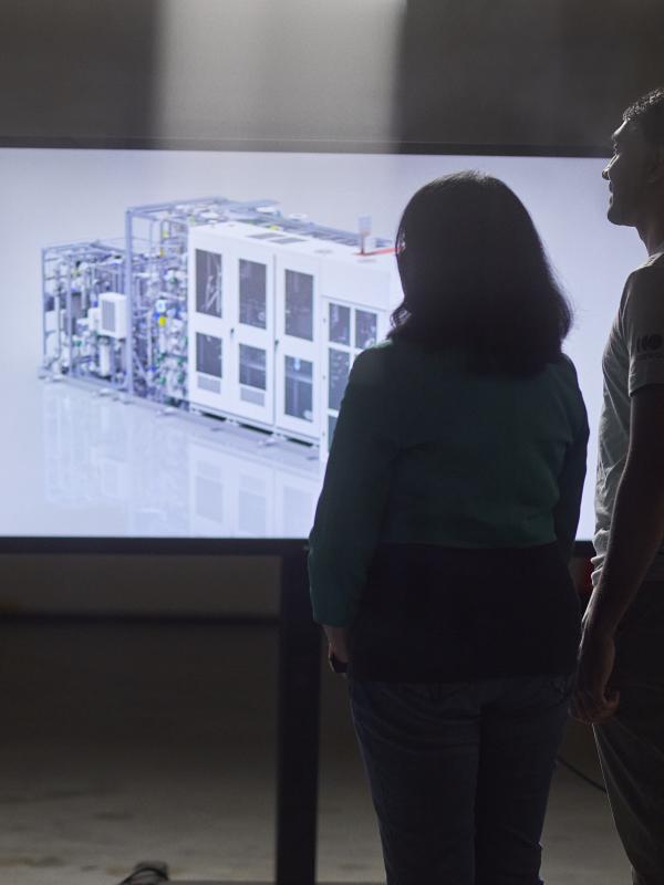Three engineers looking at 3D rendering of PEM electrolyzer
