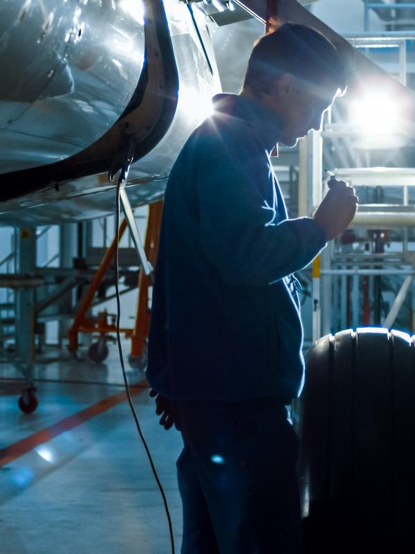 Aircraft maintenance mechanic with a flash light inspects plan chassis