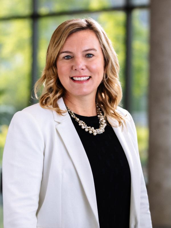 Amy Davis, President of Accelera, wearing a white blazer and black shirt; she is smiling at the camera