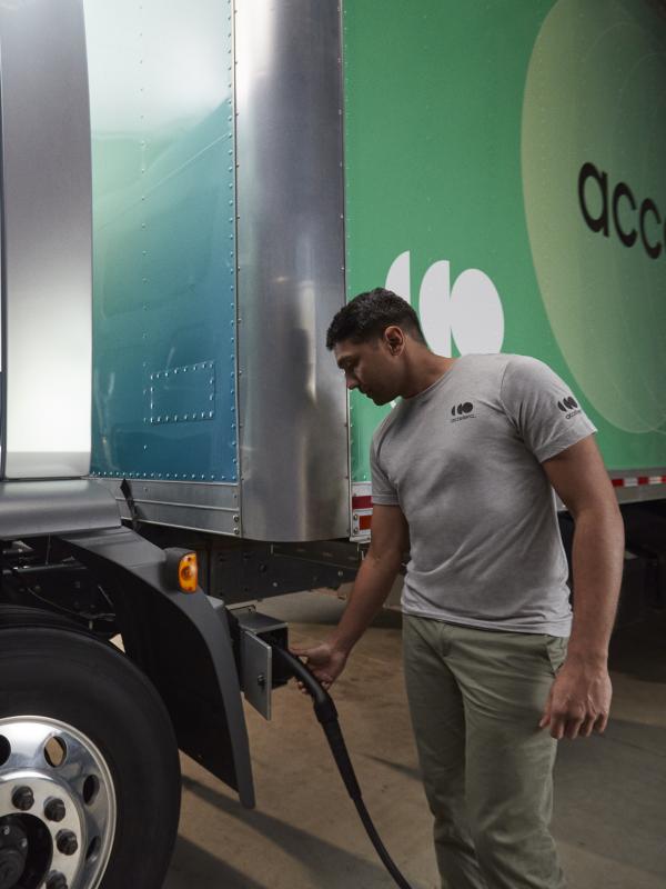 Accelera technician wearing a gray shirt and charging an electric, zero-emission truck