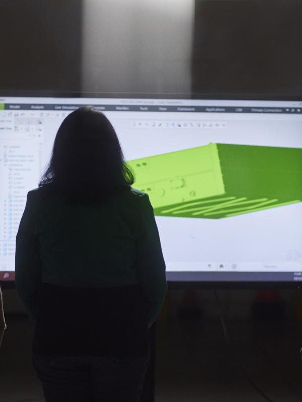 Three engineers examining a 3D rendering on a tv screen