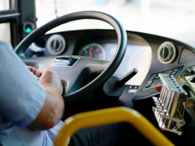 Blick auf einen Busfahrer des öffentlichen Nahverkehrs mit den Händen am Lenkrad