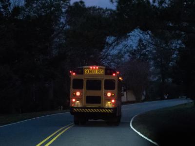 School bus driving through neighborhood before daylight