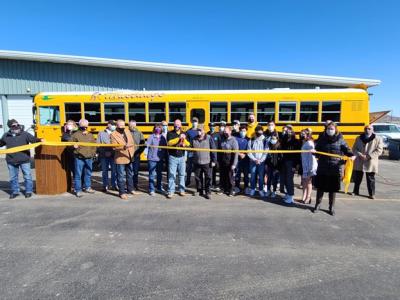 West Grand School District members cutting a yellow ribbon in front of an Accelera-powered Blue Bird school bus