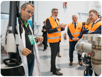Man in lab coat looking at technology while tour group listens to speaker