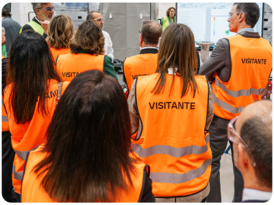 Group of people in orange visitor vests listening to man in white lab coat
