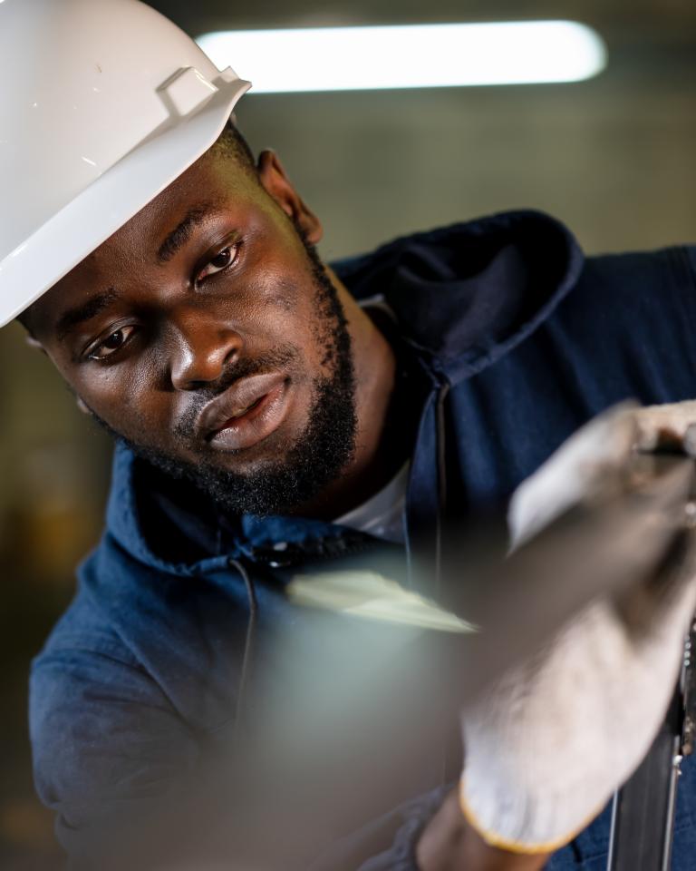 African American welder checking metal frame parts for welding accuracy