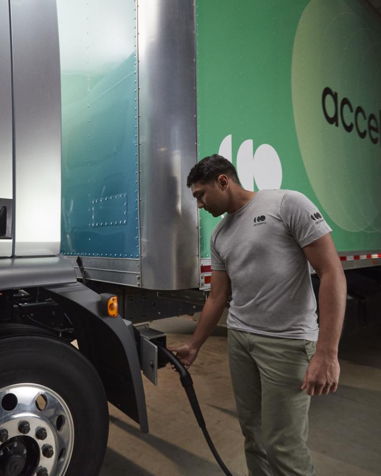 Accelera technician wearing a gray shirt and charging an electric, zero-emission truck