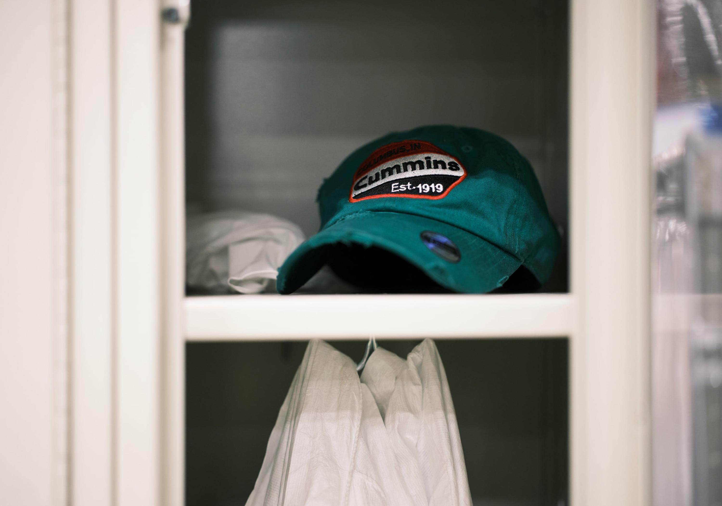 Green hate with Cummins logo sitting on a metal shelf inside a locker