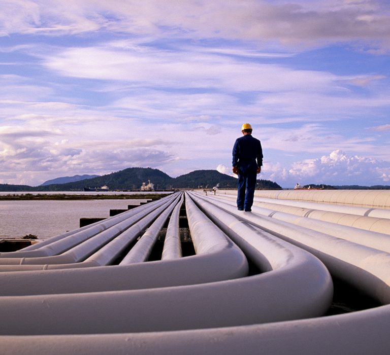 Man walking next to large pipes on the ground