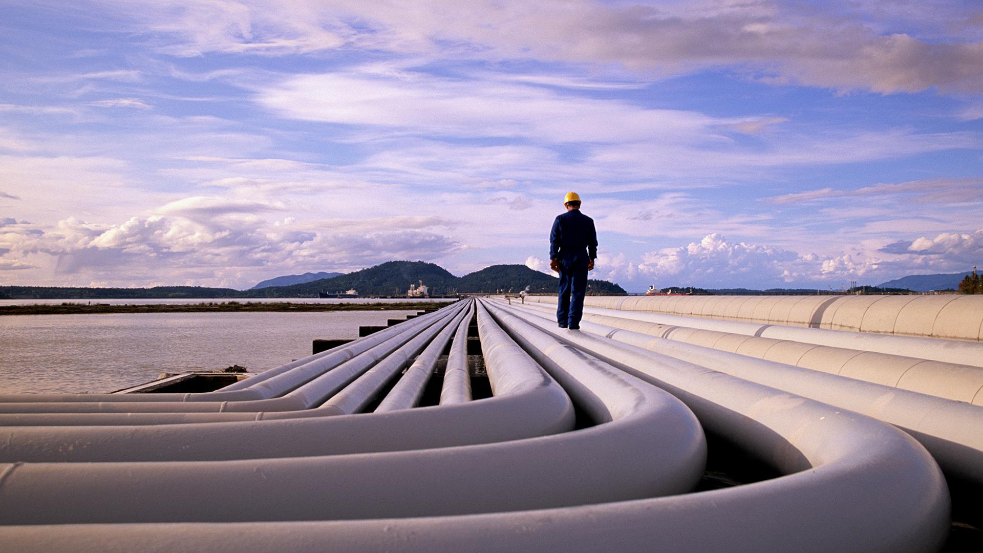 Man walking next to large pipes on the ground