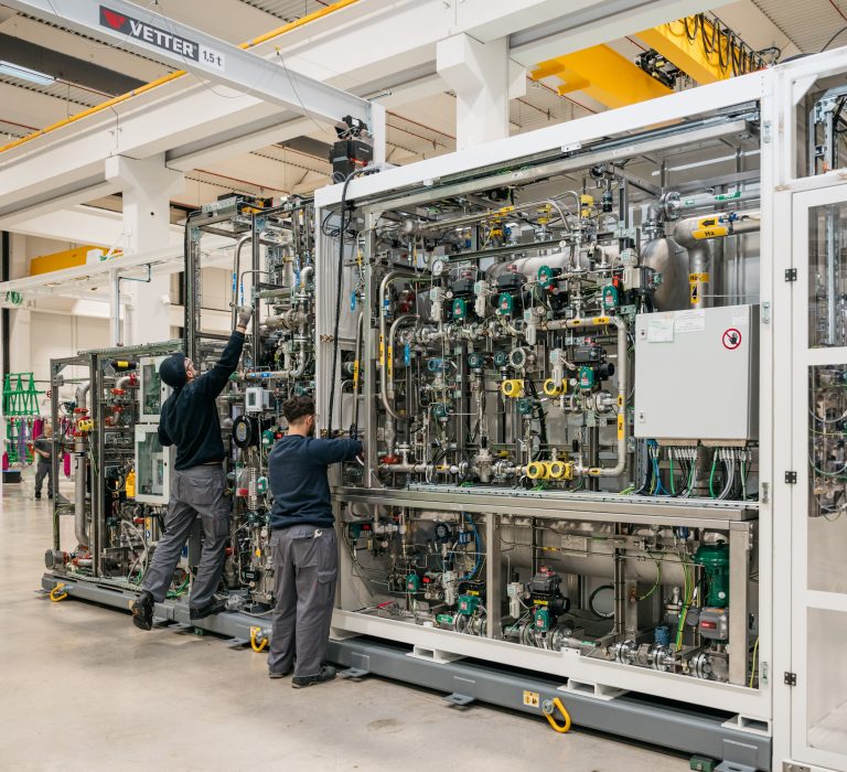 Two people working on an electrolyzer system