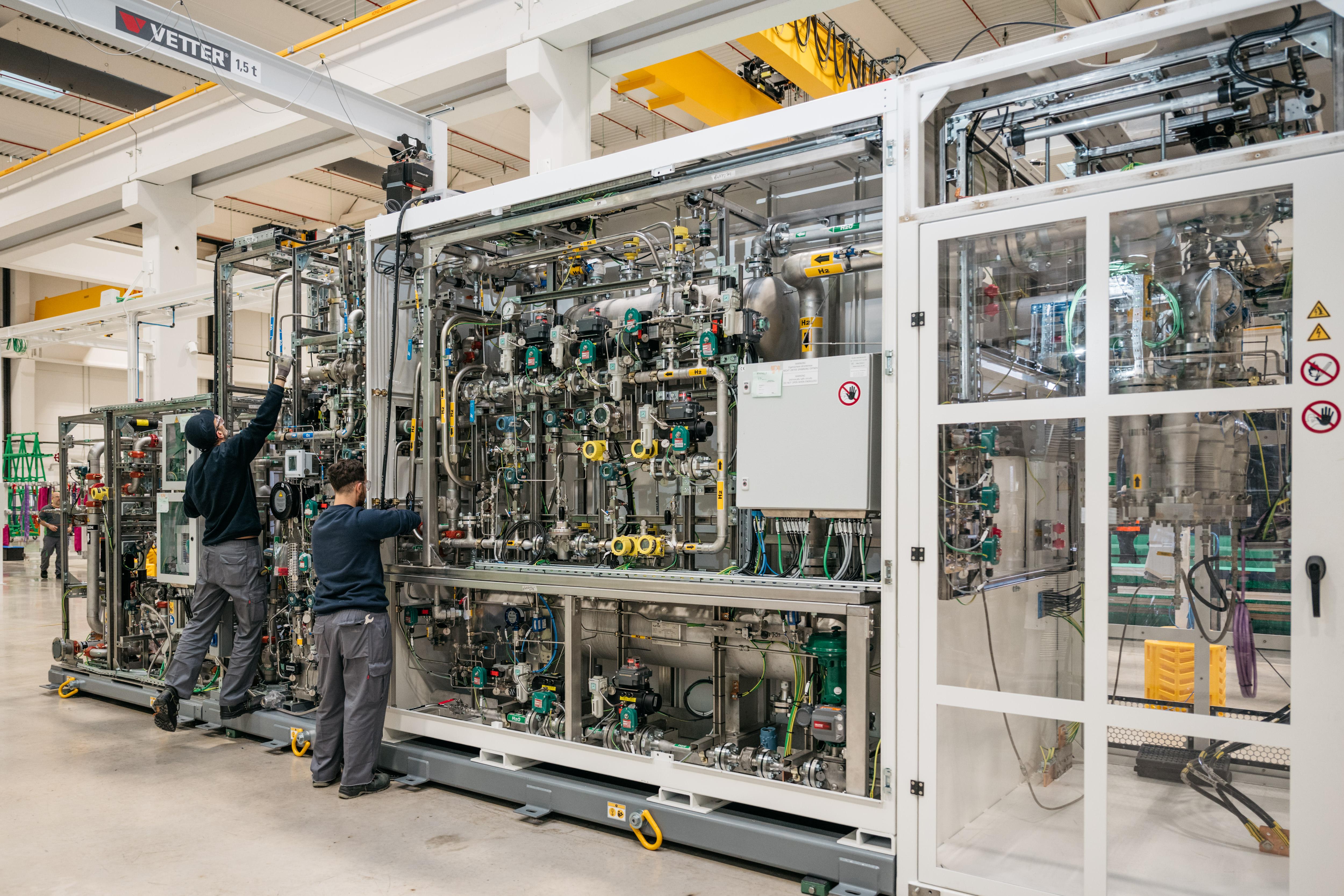 Two people working on an electrolyzer system