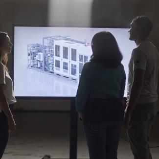 Three engineers looking at 3D rendering of PEM electrolyzer