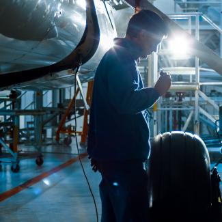 Aircraft maintenance mechanic with a flash light inspects plan chassis