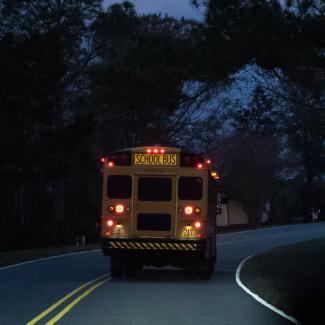 School bus driving through neighborhood before daylight
